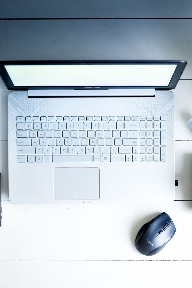 Overhead view of a desk with laptop, camera, lenses, and coffee in a minimalist setting.