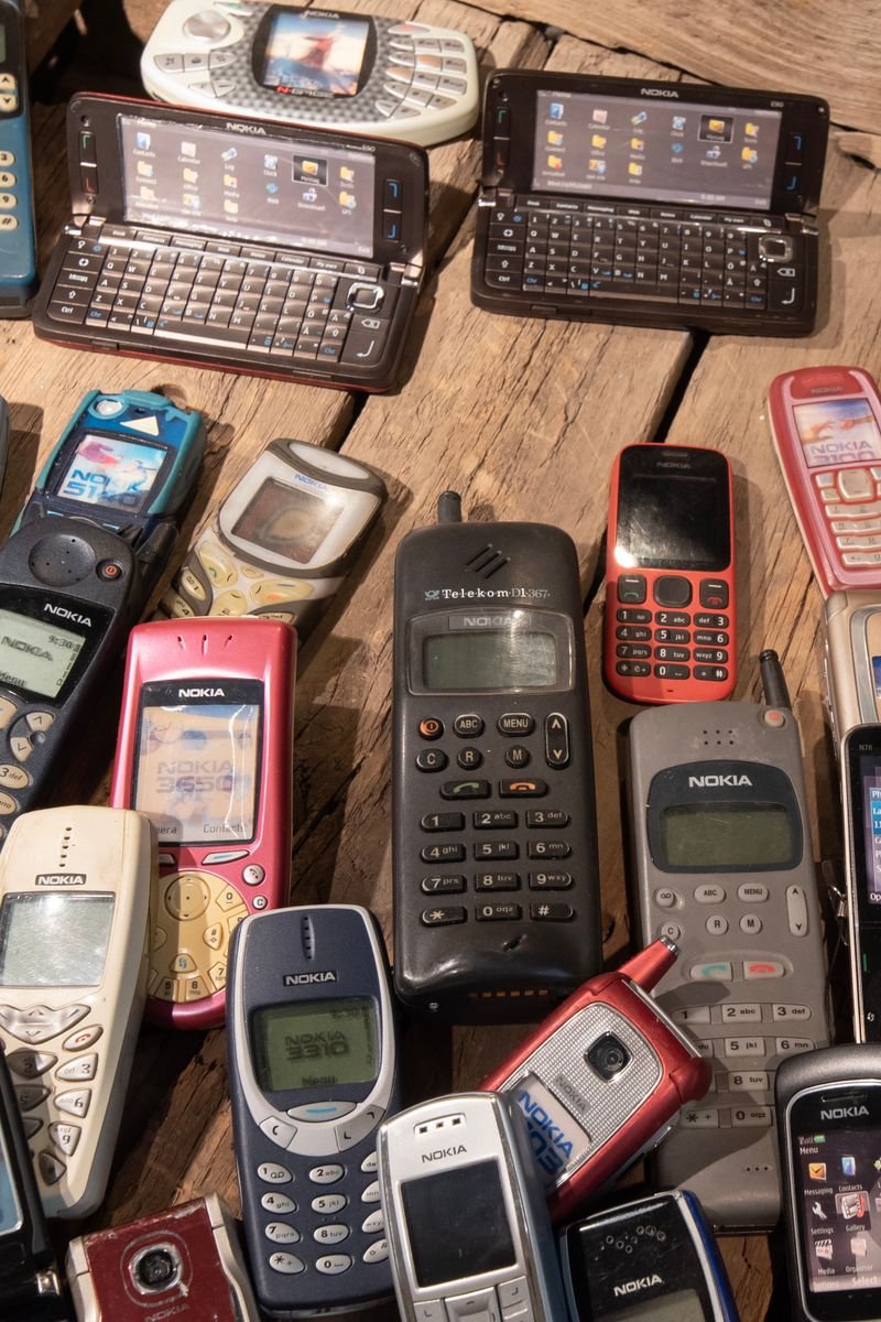 An assortment of retro mobile phones displayed on a rustic wooden surface, showcasing nostalgia.