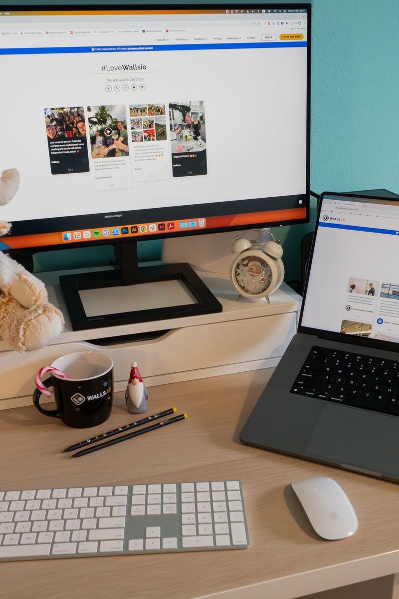 Cozy home office setup with a laptop, monitor, and teddy bear for a festive touch.
