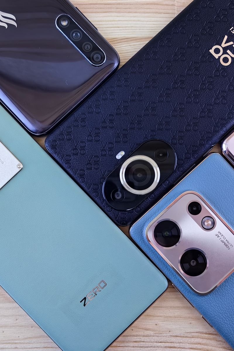 Close-up of multiple smartphones arranged on a wooden surface, showcasing variety.