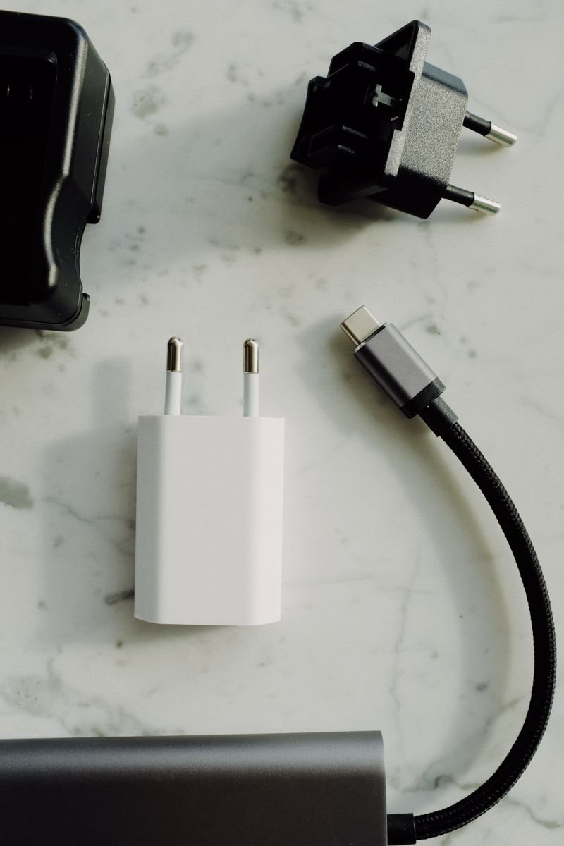 A collection of electrical plugs and a USB-C charger on a marble tabletop. Perfect for tech and electronics themes.